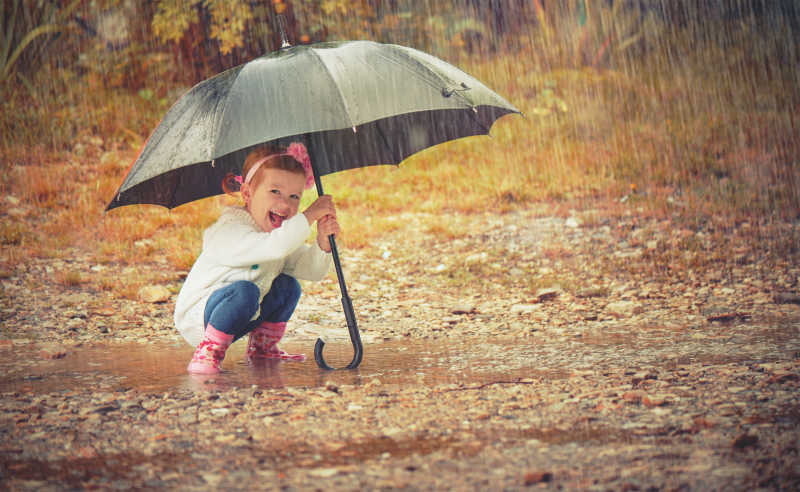 野外小孩子撑着雨水避雨
