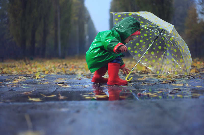 野外小孩子撑着雨水避雨