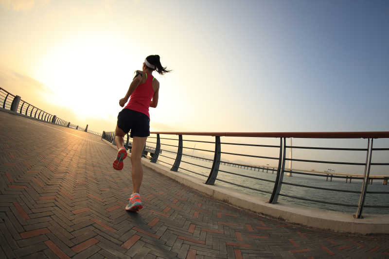 年轻的健身女子在海边跑步