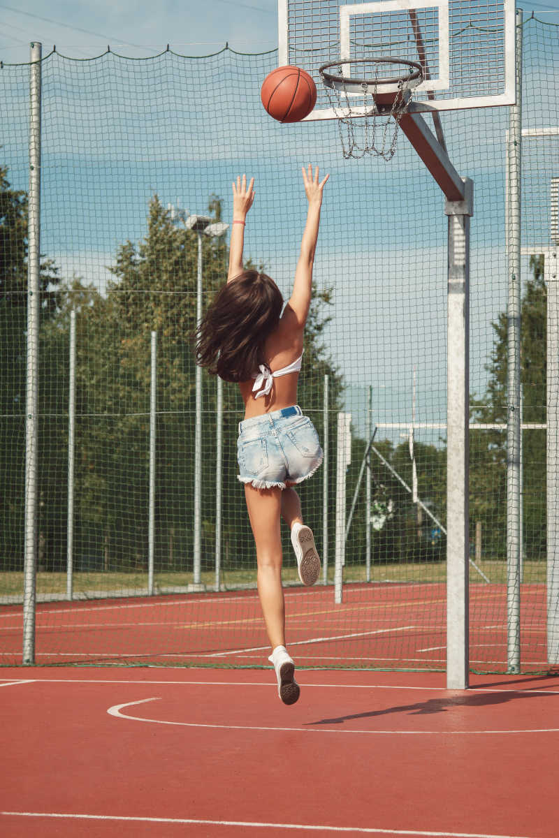 年轻性感的女孩躺在篮球场上
