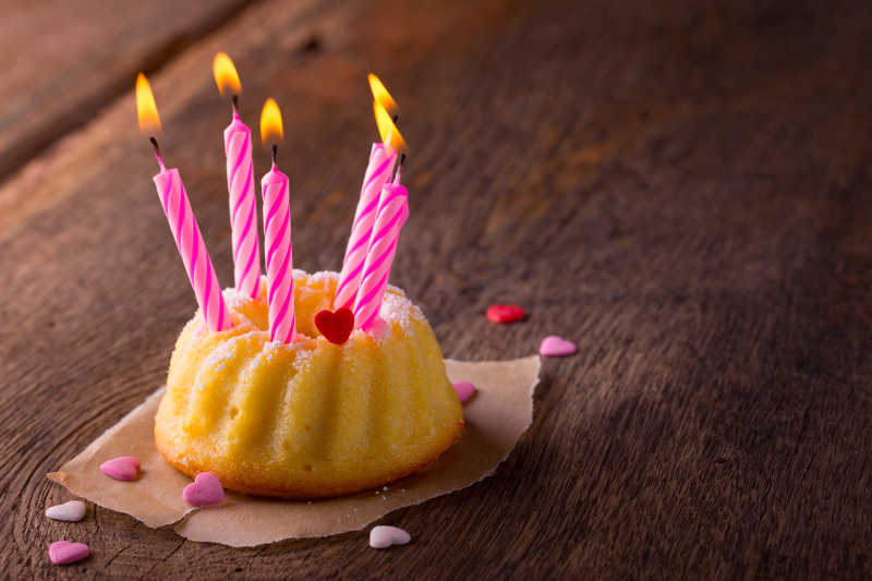 褐色木桌上的生日贺卡和小蛋糕