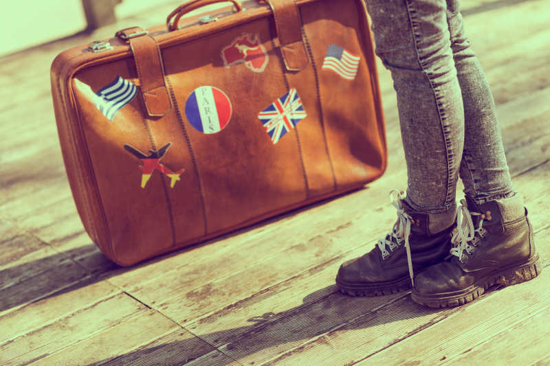 木地板背景上拎着旅行包的女孩腿部