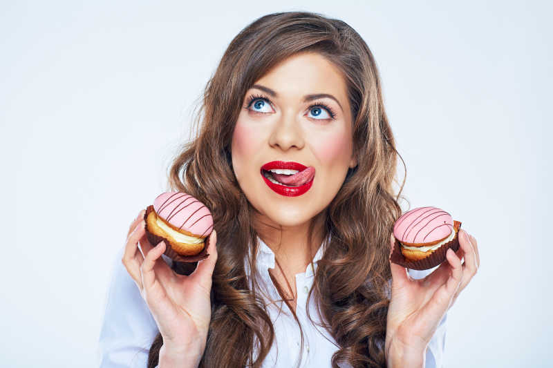 滑稽的卷发美女拿着蛋糕舔嘴唇