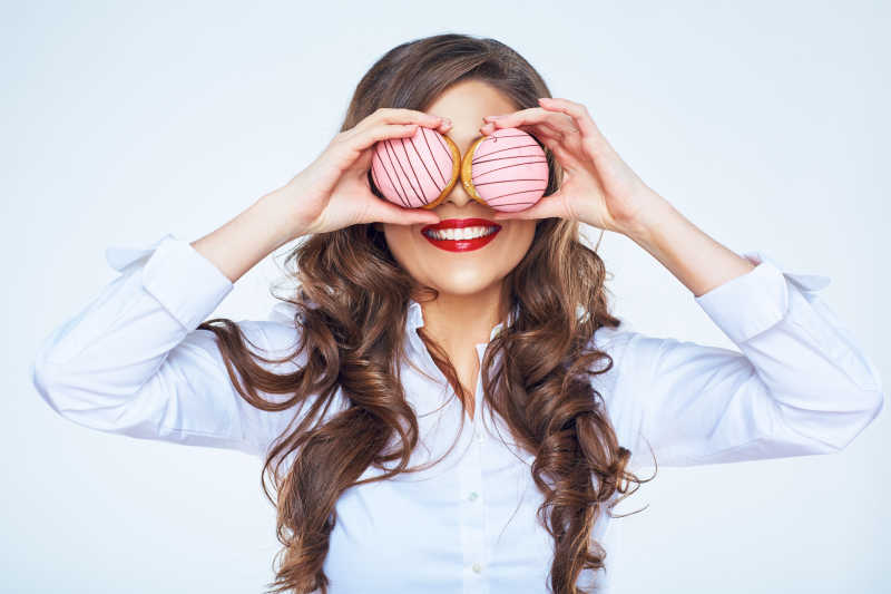 年轻美丽的卷发女子把蛋糕放在眼前