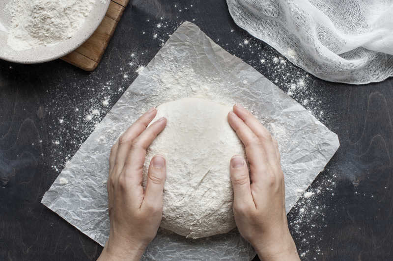 黑色背景下双手抚摸着生面团