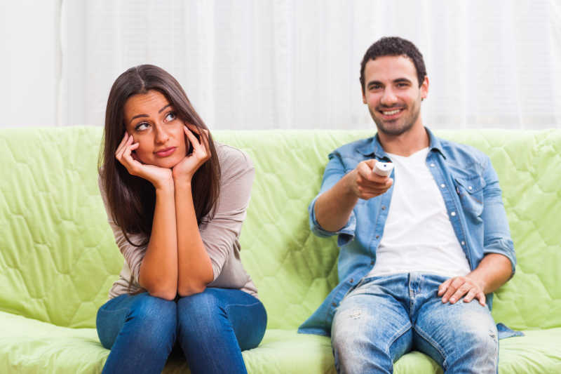 沙发上拿着遥控器的男人和托着下巴的女人