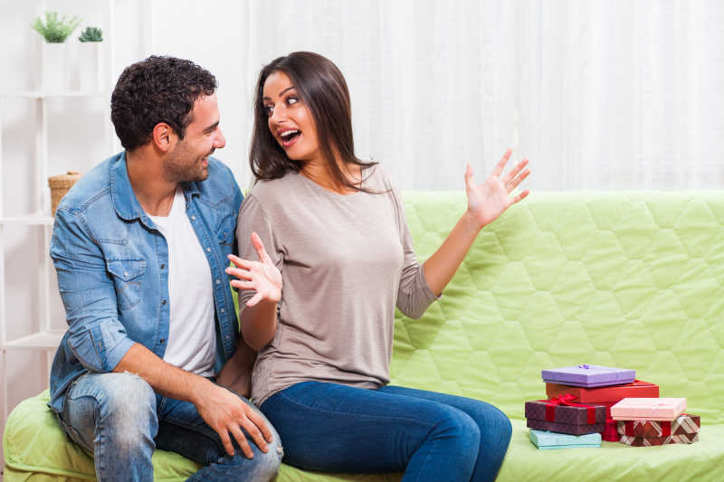 绿色沙发上聊天的夫妇和一堆礼物