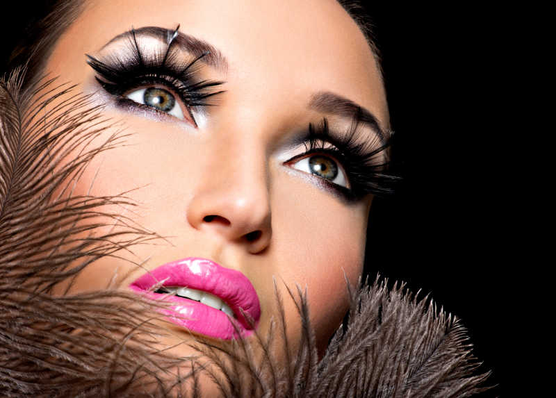 黑色羽毛背景下化浓妆的女人