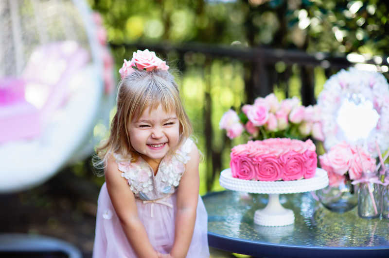 小女孩在美丽的花园里用玫瑰装饰庆祝生日派对