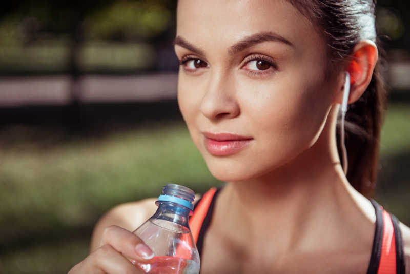 美丽女孩在训练后抱着一瓶水