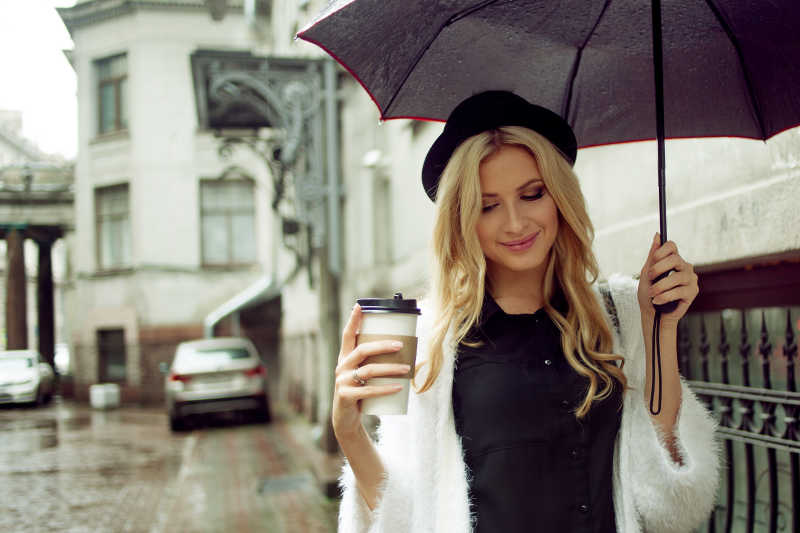 街头美女拿着咖啡打着雨伞