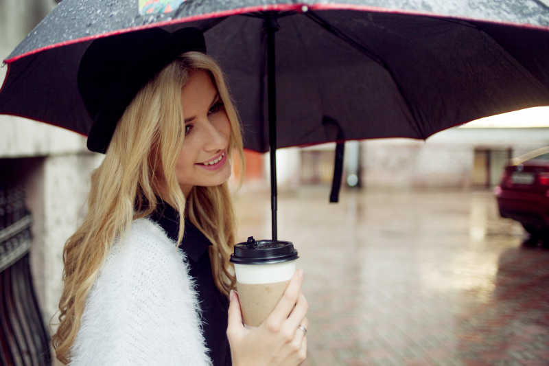 美女打着伞拿着咖啡杯