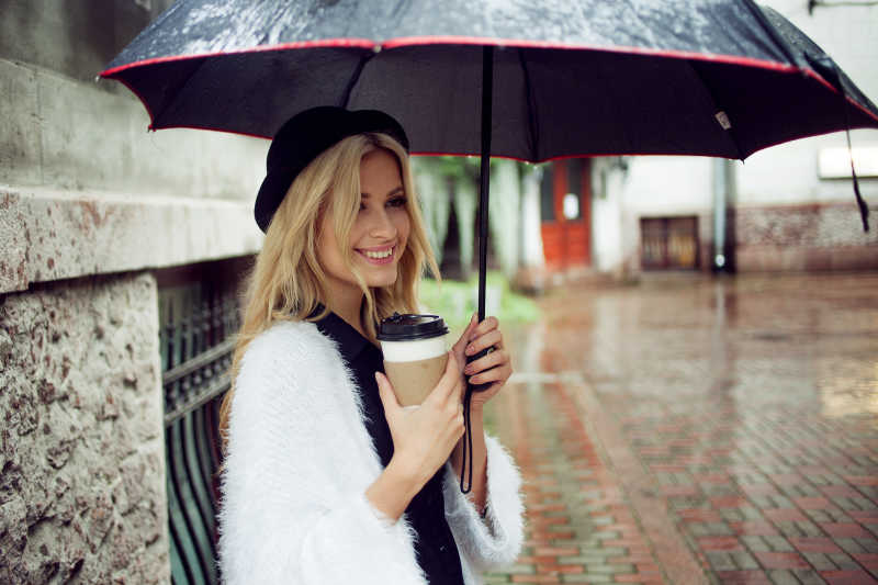 撑着雨伞喝着咖啡的女人