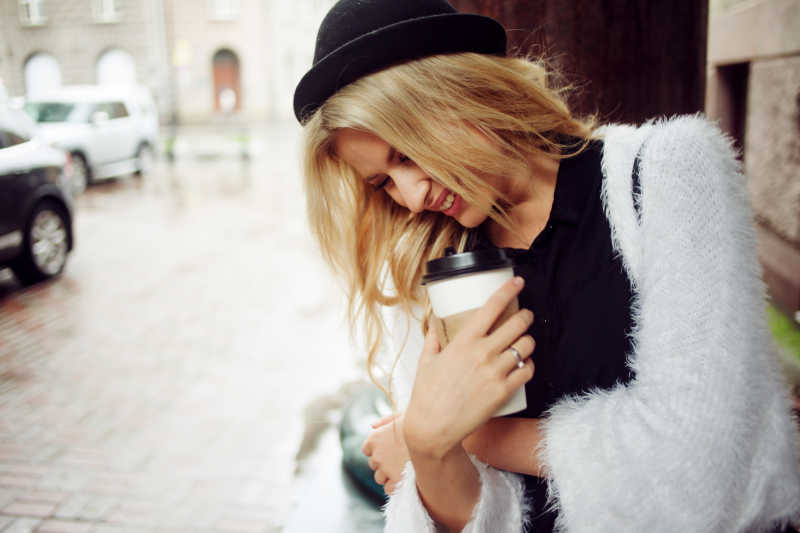 街头美丽的金发女郎抱着咖啡杯