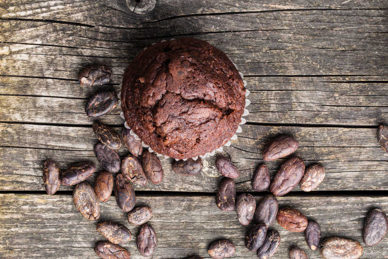 木纹理桌上的巧克力松饼和可可豆