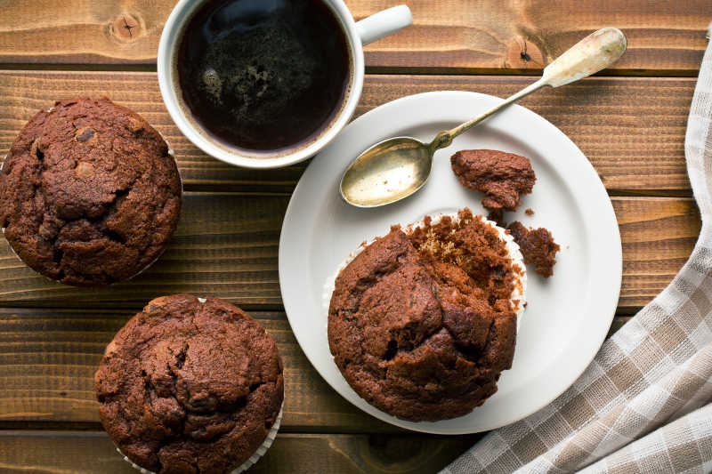 木纹理桌上白色盘子里的巧克力松饼