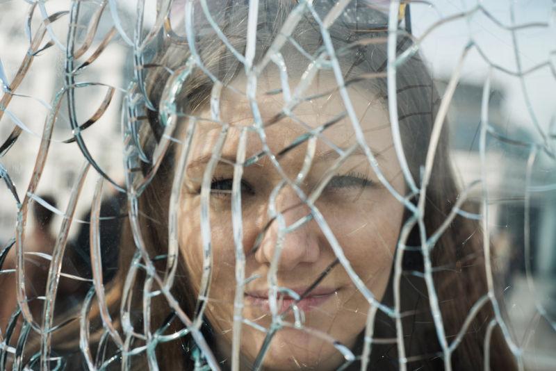 微笑年轻女子站在碎玻璃后面