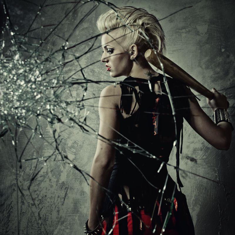 女孩拿着木棒打碎玻璃墙