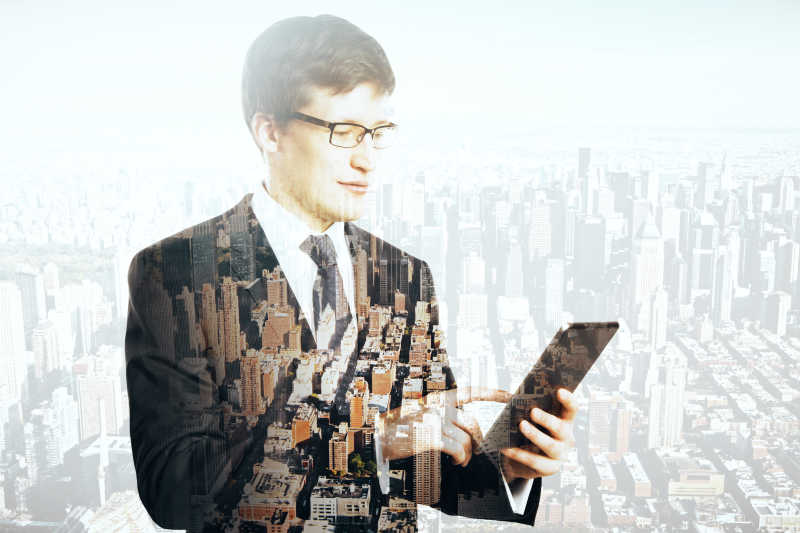 城市背景与拿着手机的商人的双重曝光