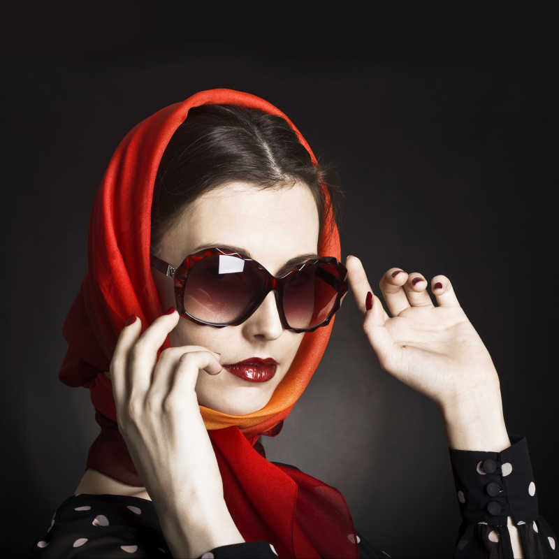 黑色背景下戴着红色时尚太阳镜美女