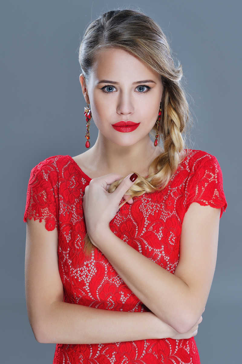 拿着自己的麻花辫看向镜头的红衣女子