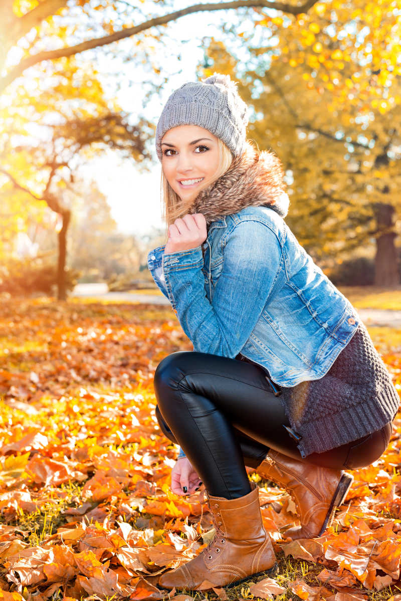 秋天树林里微笑蹲在地上的美女