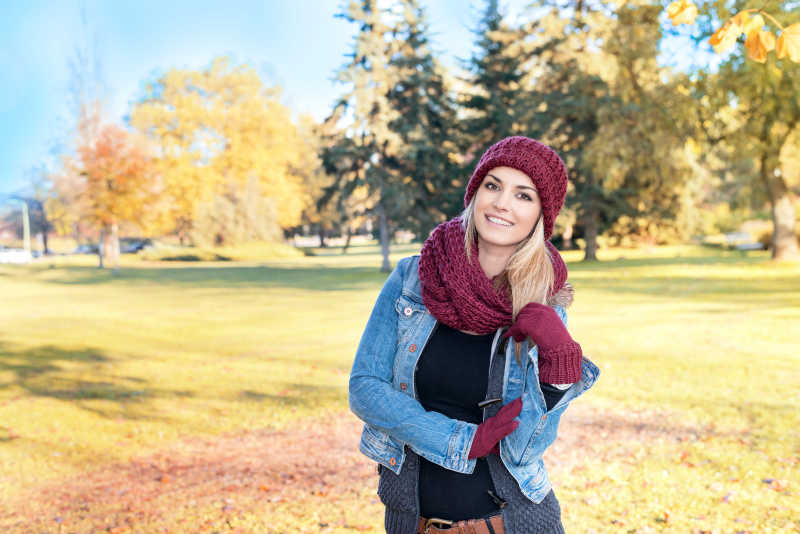 户外草坪上戴着红色帽子和围巾的美女