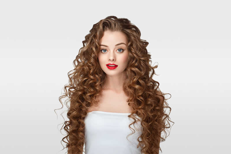 穿着白裙子的长卷发的完美红嘴唇化妆的美女肖像