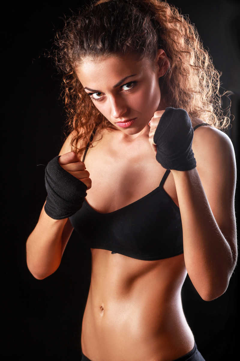 黑色背景上穿着黑色内衣打拳击的美女