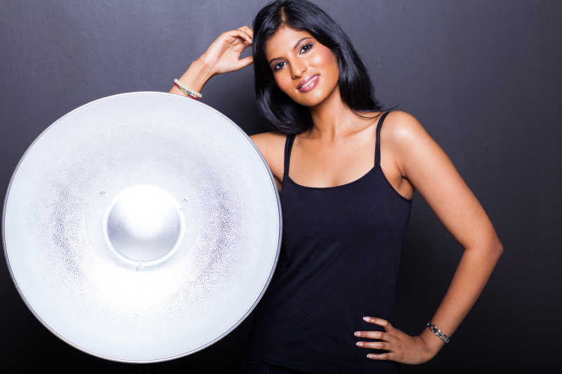 黑色背景下在巨大盘子旁拍照的美女