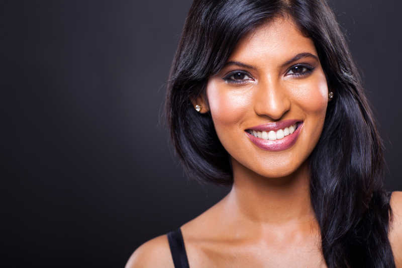 黑色背景下的微笑的美女