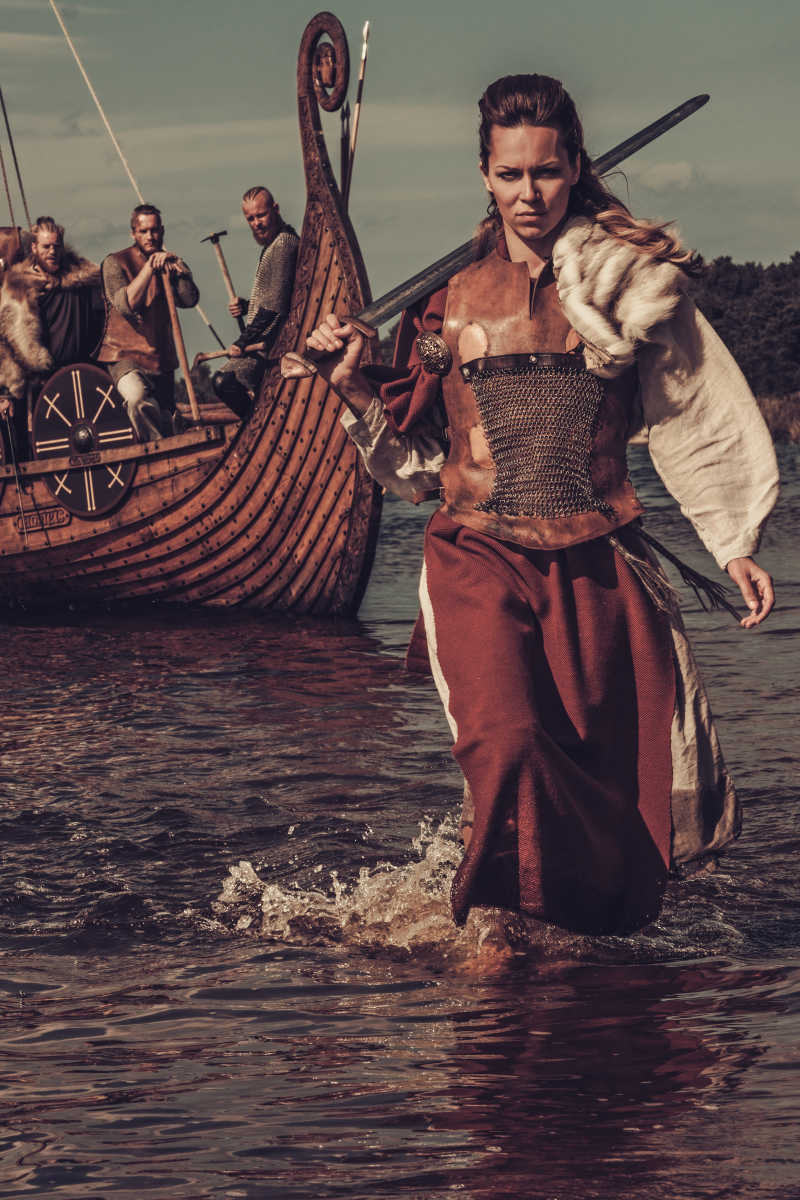 海盗船背景下扛着剑的自信维京女人