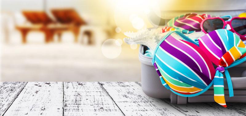 木板上行李箱里的五颜六色的比基尼