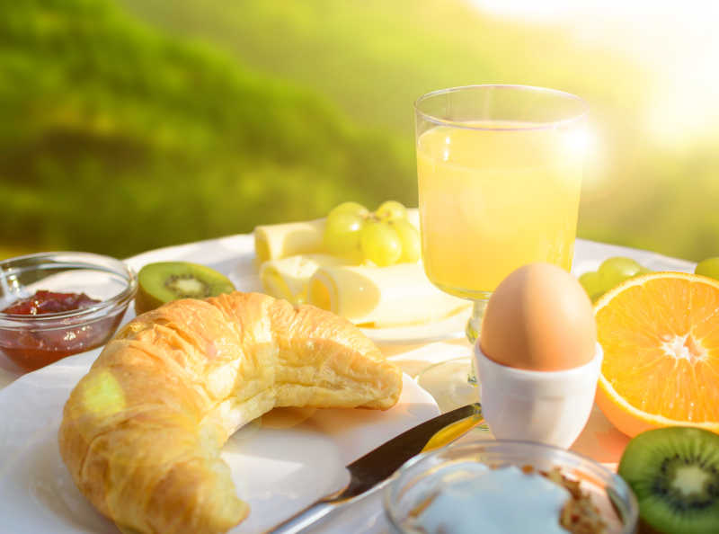 桌子上的牛角包鸡蛋橙汁早餐