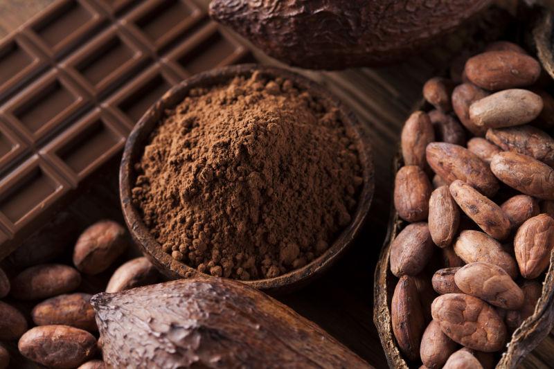 木桌上的黑色巧克力可可粉和可可豆