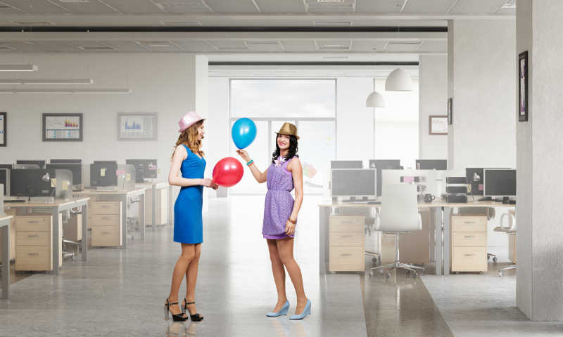 在办公室内拿着气球的两个女人