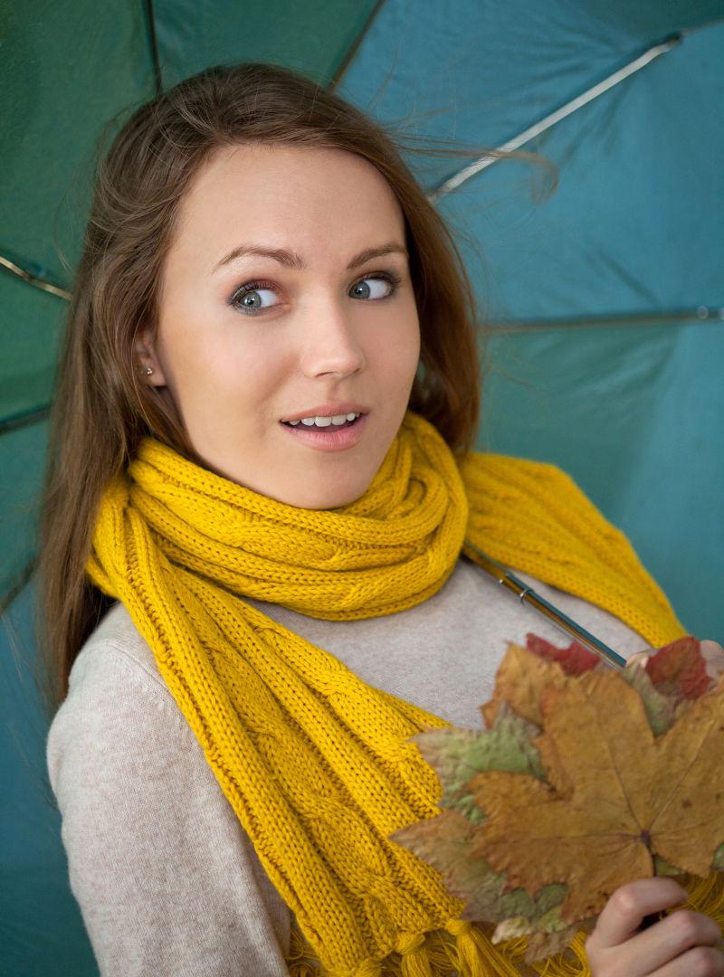 带叶子和伞的年轻女人