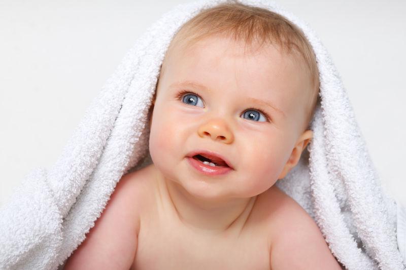 白色背景下带着白色浴巾的婴儿