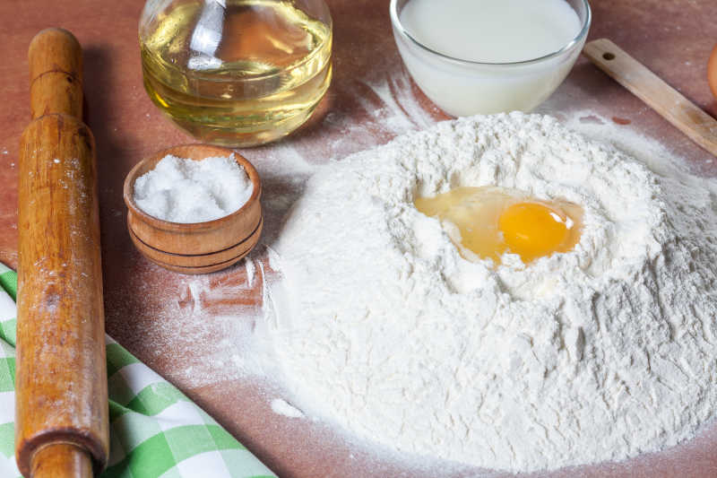 摆满制作面包的材料的桌上使用鸡蛋拌和面粉