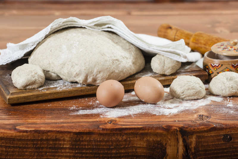 木质桌上制作面包使用的面团和鸡蛋