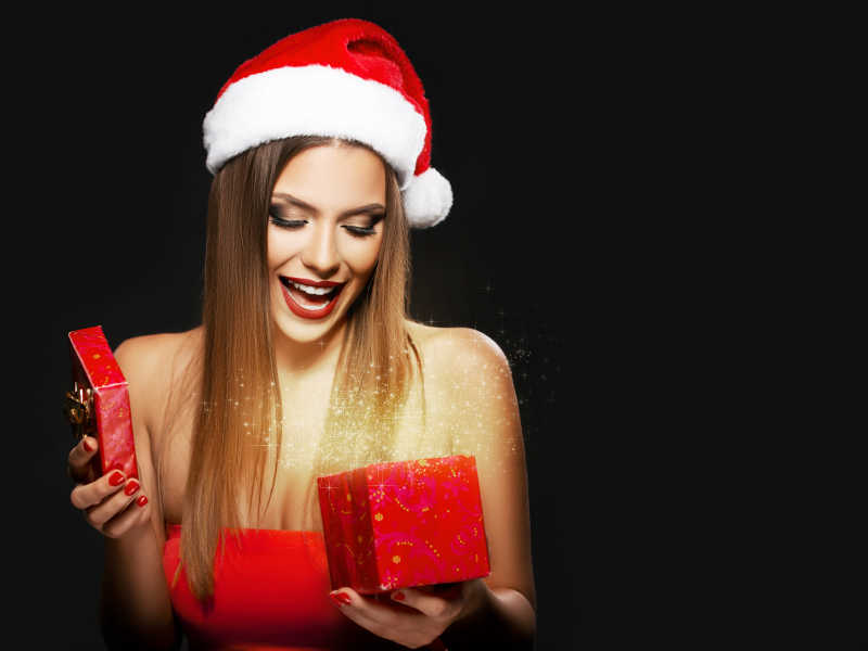 戴着圣诞帽打开礼盒的年轻美女