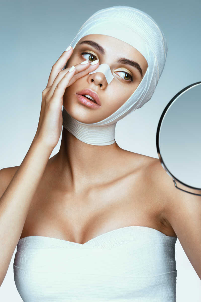 戴着医用绷带的迷人女人再照镜子