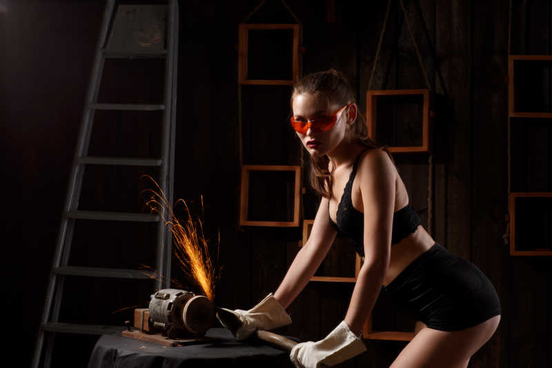 年轻漂亮黑发的女人在磨斧子