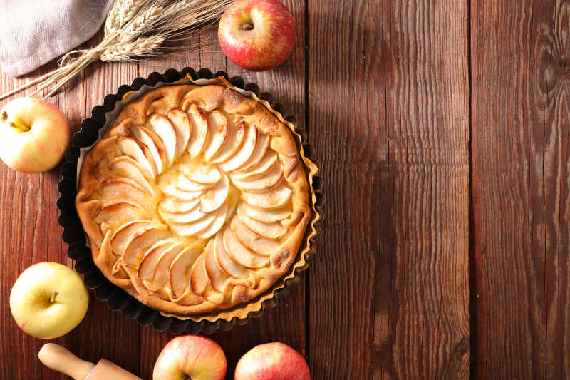木质餐桌上的苹果派和苹果