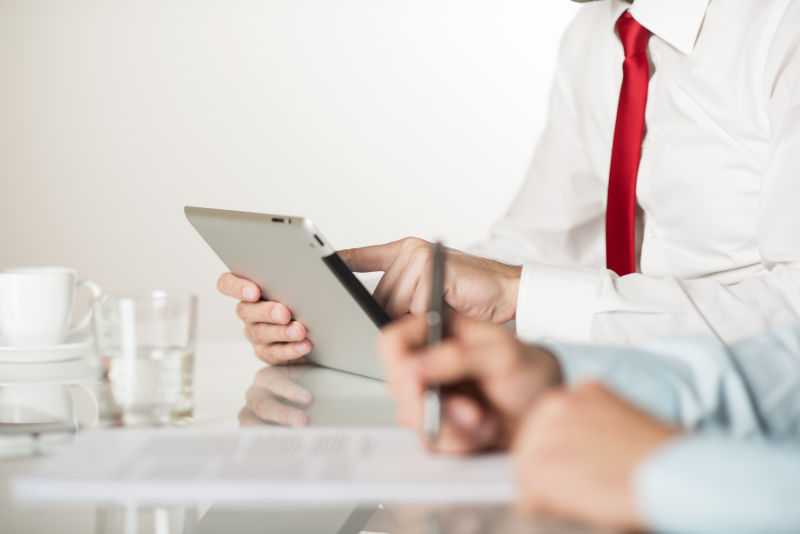 在合同签字的男子与玩平板的男子