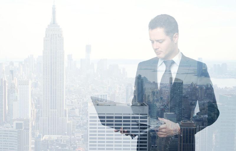 城市与看笔记本电脑的商人双重曝光