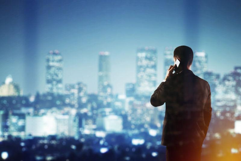 模糊的城市夜景背景下打电话的商人