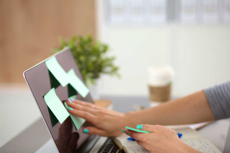 正在往笔记本电脑上贴便签的男人