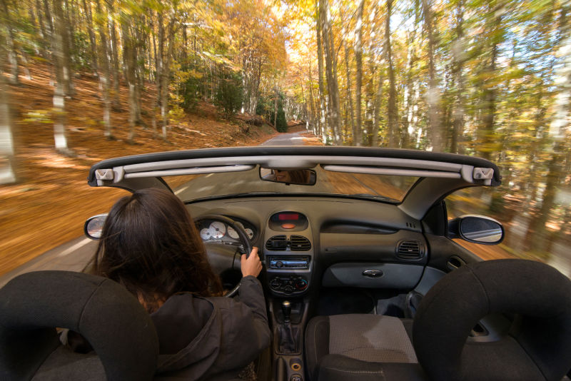 在林间小路上驾驶敞篷车的女人
