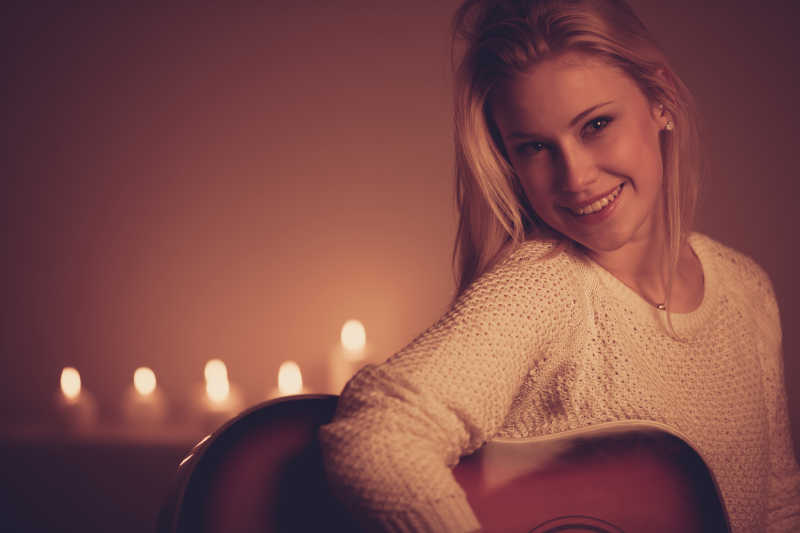 在烛光下手拿吉他的美女